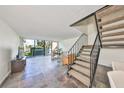 Open living area with slate floors, natural light, staircase and balcony overlooking a waterfront community at 2424 W Tampa Bay Blvd # B201, Tampa, FL 33607