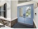 Light blue front door with glass accents and stone accents at 4544 Oak River Cir, Valrico, FL 33596