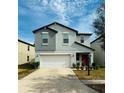 Two story home featuring an attached two car garage, red door, and manicured landscaping at 13456 Marble Sands Ct, Hudson, FL 34669
