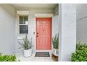Modern coral front door with potted plants at 13456 Marble Sands Ct, Hudson, FL 34669