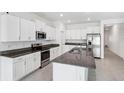 Modern kitchen with white cabinets, granite counters, and stainless steel appliances at 13580 Willow Bluestar Loop, Riverview, FL 33579