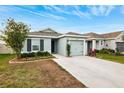 Single-story house with gray exterior, landscaping, and a two-car garage at 17071 Oval Rum Dr, Wimauma, FL 33598