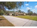 Long driveway leading to a ranch-style home with a landscaped yard at 17852 Fancy Ln, Hudson, FL 34667