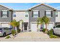 Two story townhome with gray siding, two car garage, and palm trees at 34395 Sorrel Mint Dr, Wesley Chapel, FL 33543