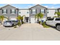 Two story townhome with gray siding, two car garage, and palm trees at 34395 Sorrel Mint Dr, Wesley Chapel, FL 33543