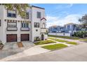 White three-story home with brown accents, two-car garage, and a front yard at 418 S Albany Ave, Tampa, FL 33606