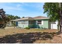 Green house exterior with mature trees and landscaping at 436 Norfolk St, Dunedin, FL 34698