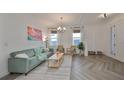 Living room features herringbone floors and a light teal couch at 935 Signet Dr, Apollo Beach, FL 33572