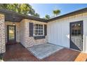 Front entrance with brick facade, tiled patio, and a gray door at 2522 Krueger Ln, Tampa, FL 33618