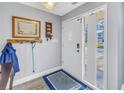 Inviting foyer features a white front door with glass panes, blue rug, coat rack, and light gray walls at 3075 Rosery Ne Rd, Largo, FL 33771