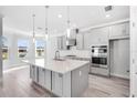 Open-concept kitchen with gray cabinets, quartz countertops, and stainless steel appliances at 33945 Landsman Loop, Wesley Chapel, FL 33543