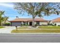 Inviting single-story home featuring a tile roof, two-car garage, and lush landscaping in a quiet community at 5809 Cruiser Way, Tampa, FL 33615