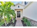 Elegant front entry with a dark brown door, brick walkway, and tropical landscaping at 6137 Voyagers Pl, Apollo Beach, FL 33572