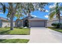 One-story home with gray exterior, two-car garage, and landscaped lawn at 31342 Philmar Ln, Wesley Chapel, FL 33543