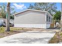 Gray manufactured home with a concrete driveway and side yard at 5234 Yellow Pine N St, St Petersburg, FL 33709