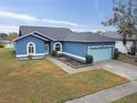 One-story blue house with a pond view, a light blue garage door, and a well-maintained lawn at 1330 Monte Lake Dr, Valrico, FL 33596