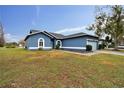 One-story blue house with a pond view, a light blue garage door, and a well-maintained lawn at 1330 Monte Lake Dr, Valrico, FL 33596