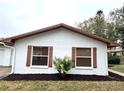 Side view showcasing the stucco exterior, brown window accents, and landscaping at 2200 Shelly Dr # C, Palm Harbor, FL 34684