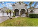 House exterior with arched entryway, landscaping, and a three-car garage at 4337 Waterford Landing Dr, Lutz, FL 33558