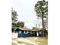 Exterior of a single-story home with dark blue siding, white trim, and a well-manicured lawn at 1701 Shore Acres Ne Blvd, St Petersburg, FL 33703