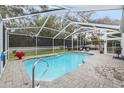 Inviting pool area with screened enclosure, patio furniture, and lush landscaping at 8535 Delaware Dr, Weeki Wachee, FL 34607