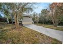 Home's exterior featuring a driveway and side view of the house with mature trees at 1512 Big Bass Dr, Tarpon Springs, FL 34689