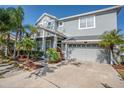 Two-story house with gray siding, palm trees, and a two-car garage at 18209 Tivoli Ln, Lutz, FL 33558