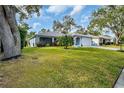 Single-story home with light blue exterior, attached garage, and lush green lawn at 3584 Oak Lake Dr, Palm Harbor, FL 34684