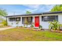 Updated ranch home with red door, landscaping, and modern exterior at 4702 W Bay Ave, Tampa, FL 33616