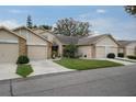 Three tan townhouses with brick accents, landscaped lawn, and attached garages at 6432 Remus Dr, New Port Richey, FL 34653