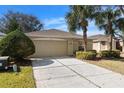 Tan house with a two-car garage and landscaping at 10833 Collar Dr, San Antonio, FL 33576