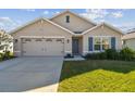 Tan house with a two-car garage and landscaped lawn at 12143 Kingsley Trl, Parrish, FL 34219