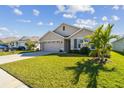 Tan house with a two-car garage and landscaped lawn at 12143 Kingsley Trl, Parrish, FL 34219