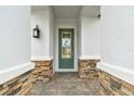Green front door with glass inserts and stone entryway at 2416 Wise River Ln, Zephyrhills, FL 33541