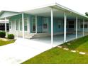 Light blue manufactured home with carport and landscaped front yard at 36819 Kiowa Ave, Zephyrhills, FL 33542