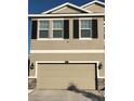 Two-story house with beige exterior, stone accents, and a three-car garage at 10913 Kidron Valley Ln, Tampa, FL 33625