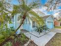 Front view of a charming light blue house with walkway and landscaping at 14721 Condor Pass, Clearwater, FL 33760