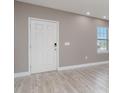 Front entry with white door, gray walls, and wood-look flooring at 2436 Sand Gables Trl, Bradenton, FL 34208
