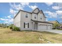 Two-story house with gray siding, three-car garage, and landscaping at 2436 Sand Gables Trl, Bradenton, FL 34208
