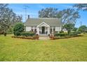 White house with a porch and lush green lawn at 4156 Mcintosh Rd, Dover, FL 33527