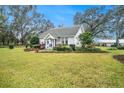 White house with a porch, green lawn, and mature trees at 4156 Mcintosh Rd, Dover, FL 33527