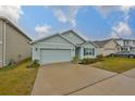 Single-story house with light blue exterior, two-car garage, and landscaping at 11520 Koti Creek Ln, Thonotosassa, FL 33592