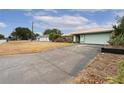 A light green house with a long driveway and a small yard at 13494 Tyringham St, Spring Hill, FL 34609