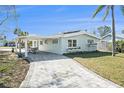 Side view of a light teal home with a covered patio, paved walkway and nicely landscaped lawn at 17602 Sterling Ter, Redington Shores, FL 33708