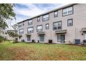 Back view of townhouses showcasing a grassy backyard and AC units at 2547 Lexington Oak Dr, Brandon, FL 33511