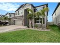 Two-story house with stone accents and a paver driveway at 3071 Marine Grass Dr, Wimauma, FL 33598