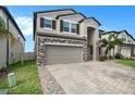 Two-story house with stone accents and a paver driveway at 3071 Marine Grass Dr, Wimauma, FL 33598