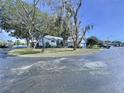 View of the house highlighting its position on a corner lot with surrounding mature trees and landscaping at 7923 Leighton Cir, New Port Richey, FL 34654