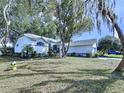 Well-maintained white home showing the facade, landscaping, and partial view of the lawn and mature trees at 7923 Leighton Cir, New Port Richey, FL 34654