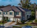 Lovely townhome showcasing a stone accent wall, attached garage, and manicured landscaping in a desirable community at 6972 Ripple Pond Loop, Zephyrhills, FL 33541